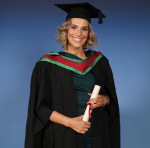 The image features a person wearing a graduation gown, The individual is celebrating their academic achievements, as indicated by the mortarboard hat and diploma.